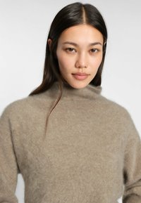 Ljusbrun, mohairblandad polotröja med en mjuk, fluffig textur och avslappnad passform, med sänkt axel och minimala sömmar.