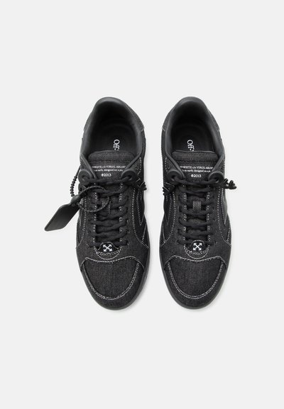 Ζευγάρι μαύρα sneakers χαμηλής κοπής με λευκό ράψιμο, μαύρα κορδόνια, επώνυμες ετικέτες και χαρακτηριστικό λογότυπο στην περιοχή των δακτύλων.