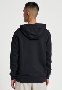 Czarna bluza z kapturem o przestronnym kroju, z prążkowanymi mankietami i hemem, wykonana z miękkiego materiału bawełnianego. Charakteryzuje się luźnym fasonem i minimalistycznym designem.