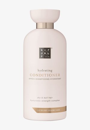 Bouteille de conditioner hydratant en rose doux, de forme arrondie avec une touche dorée au cou. L'étiquette affiche des détails en or et en noir.