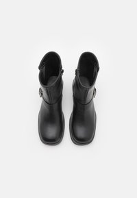 Czarne skórzane botki za kostkę o gładkiej teksturze, z okrągłym noskiem, bocznymi zamkami błyskawicznymi oraz ozdobnymi elementami metalowymi. Płaskie podeszwy i średnia wysokość.