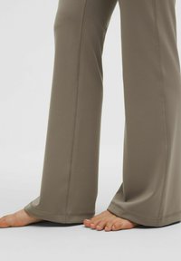 Wide-leg, taupe pants made from soft, stretchy fabric. Features visible stitching along the sides, with a smooth texture and relaxed fit.