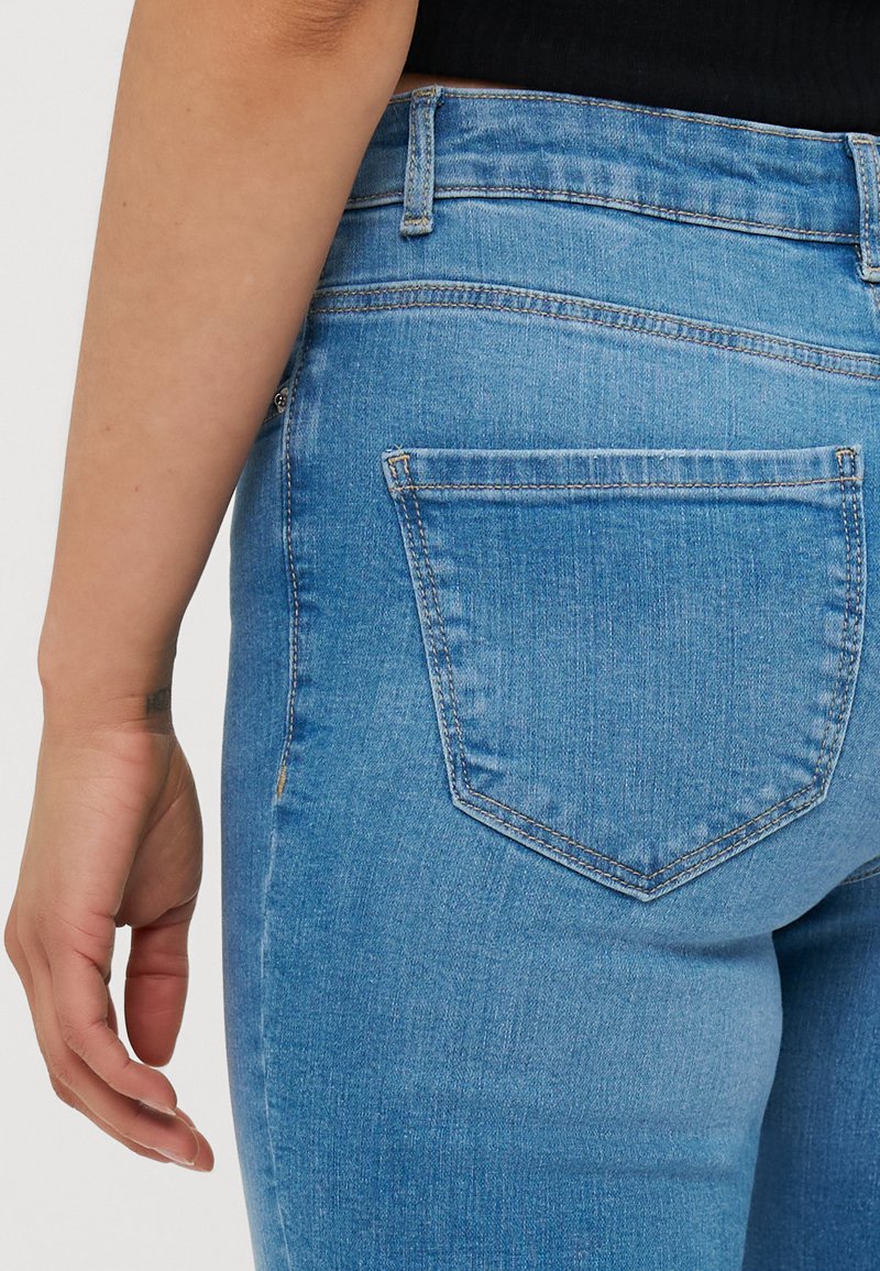 Hellblaue Denim-Jeans mit tailliertem Schnitt, einer Gesäßtasche mit gesticktem Rand und einer subtilen Textur.