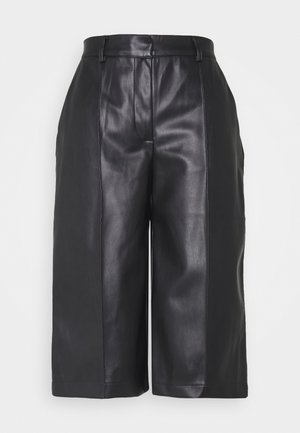 Pantalons en cuir noir de style culotte avec une texture lisse, un design à jambes larges et des poches latérales pour plus de fonctionnalité. Détails de taille sur mesure.