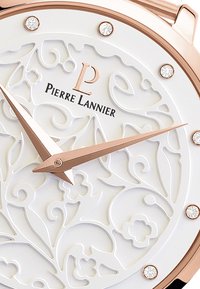 Reloj de pulsera en oro rosa con un dial blanco con relieve de flores, que presenta un logo, dos manecillas y marcadores de hora de cristal. Detalles de diseño elegantes e intrincados.