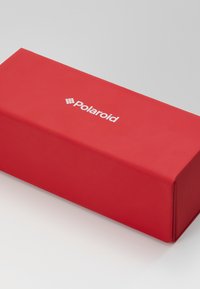 Cutie roșie rectangulară cu o textură netedă, având un logo alb Polaroid centrat pe față. Fără detalii sau modele suplimentare vizibile.