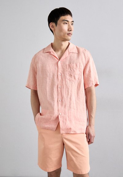 Camicia button-up rosa chiaro a maniche corte, realizzata in tessuto текстurizzato, con una tasca sul petto. Abbinata a pantaloni corti rosa chiaro coordinati.