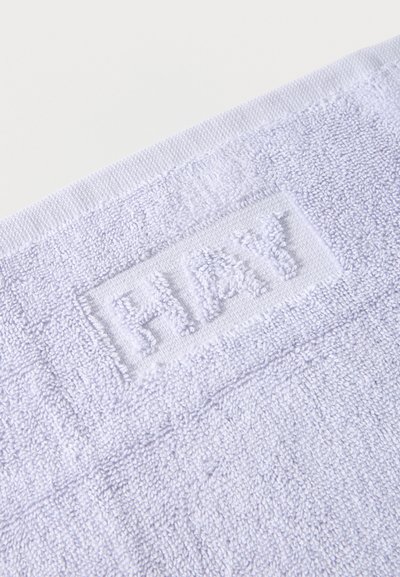 Λευκή πετσέτα μπάνιου με υφή, με τη λέξη "HAY" ανάγλυφη στο ύφασμα κοντά στην άκρη, πάνω σε απλό φόντο.