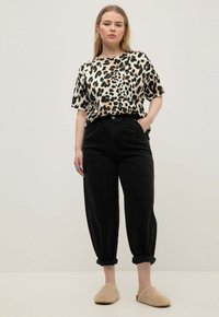 Camicia a maniche corte con stampa leopardata, pantaloni neri a vita alta, con risvolti, e pantofole in peluche beige. Tessuto liscio con una vestibilità rilassata.