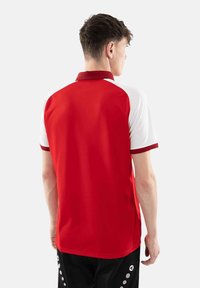 Polo rosso e bianco con colletto a coste, caratterizzato da un design color block, maniche corte e una consistenza liscia.