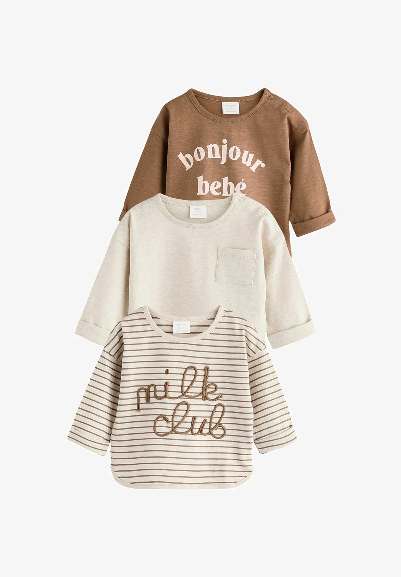 Trīs garām piedurknēm T-krekli zīdaiņiem: brūns ar baltu tekstu, bēšs ar kabatu un svītrains bēšs ar brūnu "piena kluba" izšuvumu.