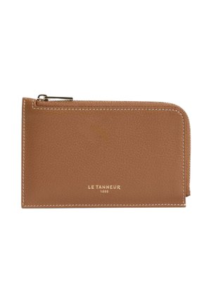 Bolsa rectangular marrón de cuero con cremallera, costuras blancas y el texto "LE TANNEUR 1898" en relieve en dorado en el frente.