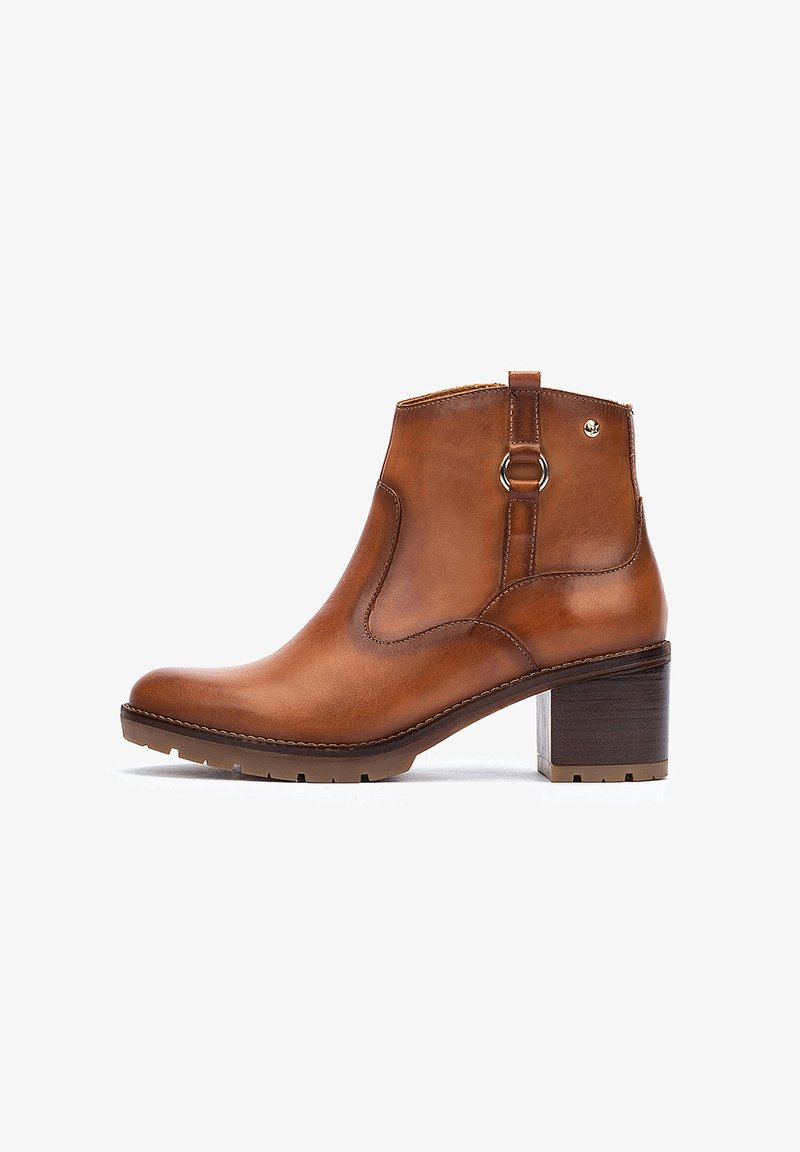 Bottine en cuir marron avec un bout arrondi, fermeture éclair sur le côté et talon carré. Présente des détails de couture et un petit accent en métal à l'arrière.