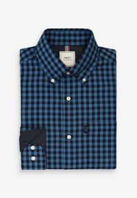 Niebiesko-czarna kraciasta koszula z kołnierzykiem na guziki, białymi guzikami oraz kontrastującym granatowym mankietem w groszki. Na dole znajduje się detal z logo.