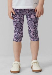 Paarse leggings met vlinder- en panterprintpatronen, met een aansluitend ontwerp en verkorte lengte, gecombineerd met witte sneakers.