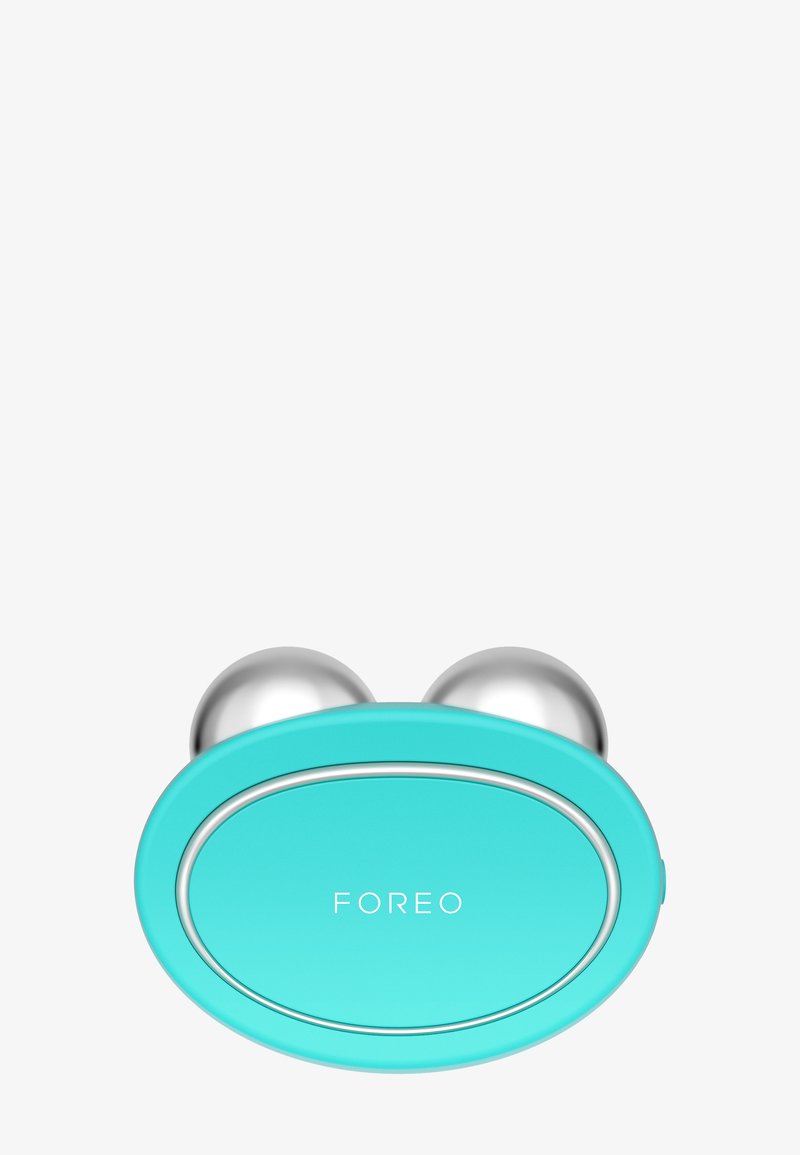 Turkosa ansiktsapparat med två silverfärgade sfäriska tillbehör, en slät rundad kropp och en liten oval logotyp märkt "FOREO".