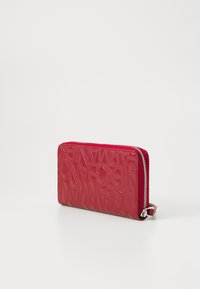 Red embossed leather wallet with a textured design, featuring a silver zip closure and a small loop for attachment.