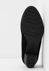 Semelle de chaussure noire avec grip à motifs, petit talon bloc, marquages de taille et texte "Soft FLEX" au centre de la semelle.