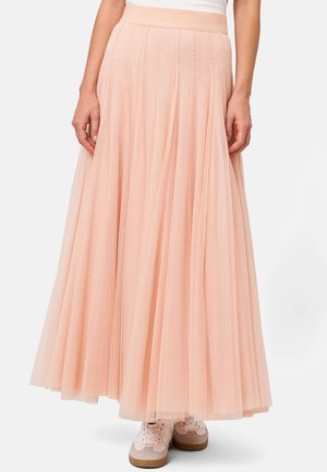 Longue jupe en tulle rose avec un design plissé, texture douce, large taille, silhouette en couches, associée à des baskets rose pâle.