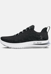 Chaussures de sport noires avec une tige texturée, des accents gris et une semelle blanche, présentant un logo "FLOW" sur le côté et un design à lacets.