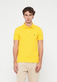Gul polo skjorte laget av bomull, med en klassisk krage, korte ermer, tre-knapp lukking, og en liten logo detalj på brystet.