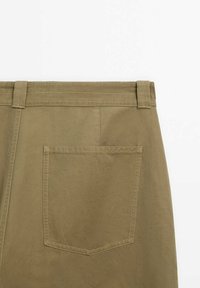 Vue arrière d'un pantalon de couleur kaki, avec une grande poche plaquée rectangulaire et des passants de ceinture à la taille.