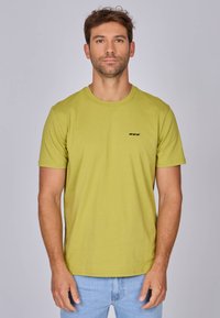 T-shirt en coton vert lime avec un col rond et des manches courtes. Présente un petit motif graphique noir sur la poitrine. Texture douce.