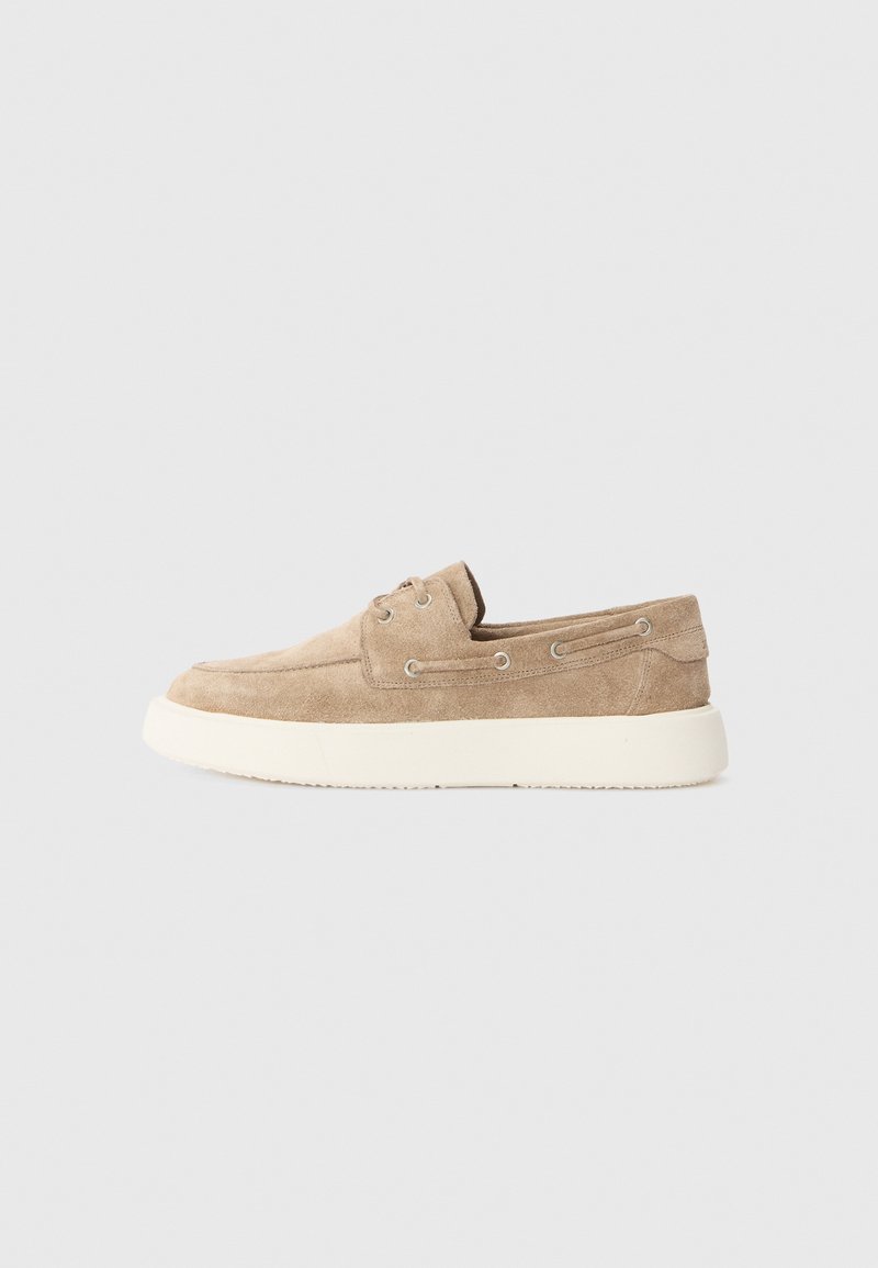 Beige nubuk slip-on cipők fehér gumitalppal, az oldalán két pár fém fűzőlyukkal és sima felülettel.