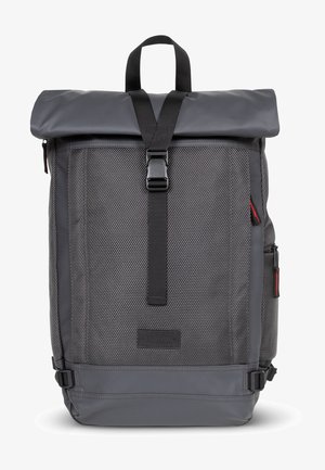 Gray roll-top backpack with a textured fabric, adjustable straps, and buckle closure. Features side pockets and a branded patch.