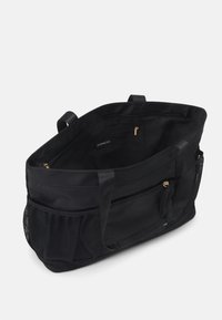 Bolso tote negro hecho de tela duradera con un interior espacioso, presenta un bolsillo con cremallera dorado y un bolsillo lateral de malla para almacenamiento.