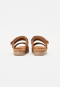 Brune semskede sandaler med åpen bak og flere justerbare stropper, som har en polstret såle og en lett gummisåle.