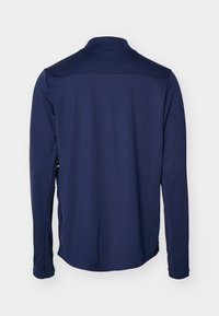 Marineblaue Langarm-Polohemd mit Stehkragen, glatter Textur und seitlichen Schlitzen. Mit einer Nahtdetailierung über den oberen Rücken.