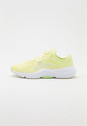 Jasnożółty but do biegania Nike z białą podeszwą i zielonym akcentem, siateczkowa cholewka i sznurówki, pokazany z lewej strony na białym tle.