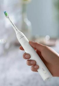 Spazzolino elettrico bianco con un design slim, manico arrotondato e testina di setole blu-verdi. Caratterizzato da un pulsante di accensione/spegnimento e un indicatore di carica.