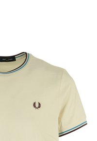T-shirt color crema con collo a girocollo a costine, caratterizzato da una bordatura a righe marroni e blu e un piccolo logo ricamato sul petto.