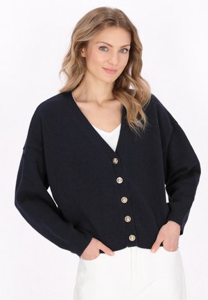Marineblauwe cardigan met een V-hals, oversized pasvorm, geribde manchetten en zes goudkleurige knopen. Soepele textuur, zijzakken en casual stijl.