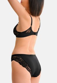 Ensemble de lingerie noir comprenant un soutien-gorge à bretelles ajustables avec une finition en dentelle et une culotte taille haute assortie, mettant en valeur des détails en dentelle florale.