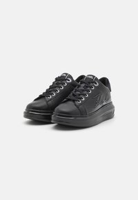 Black sneakers with a smooth leather upper, contrasting stitching, round toe, flat laces, and signature logo embossed on the side.