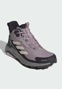 Fialová a černá turistická obuv s texturovaným textilním svrškem, zesílenou špičkou a robustní podrážkou. Obsahuje voděodolné detaily a tkaničky.