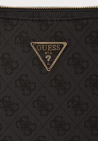 Mustakankainen laukku, jossa on kohokuvioitu kuvio ja kultainen kolmiomainen logo. Varustettu ylhäällä vetoketjulla ja tekstuuripinnalla.