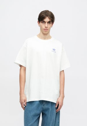 Λευκό βαμβακερό T-shirt με κοντά μανίκια, με μικρό μπλε λογότυπο της Adidas στο αριστερό στήθος. Χαλαρή εφαρμογή και απλός σχεδιασμός.