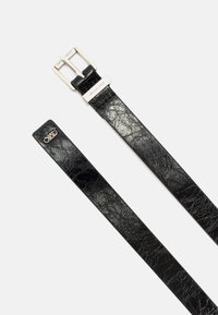 Zwarte leren riem met een gestructureerde afwerking. Voorzien van een zilveren metalen gesp en een reliëflog op de punt. Eenvoudig en functioneel ontwerp.