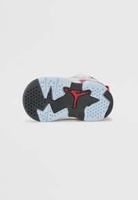 Air Jordan-sko med sort, rød og lyseblå gummisåle, preget av et Jumpman-logo og teksturert overflate med varierte mønstre.