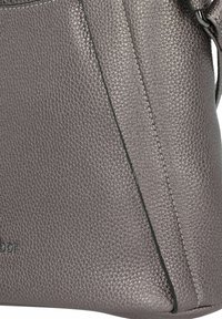 Bolso de mano de cuero texturizado gris con forma triangular, que presenta costuras en contraste y una correa delgada y ajustable.