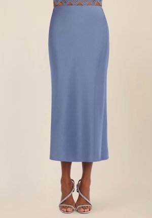 Blaue Midirock mit hoher Taille, kombiniert mit silbernen, mit Riemchen versehenen High-Heel-Sandalen an einer stehenden Person.