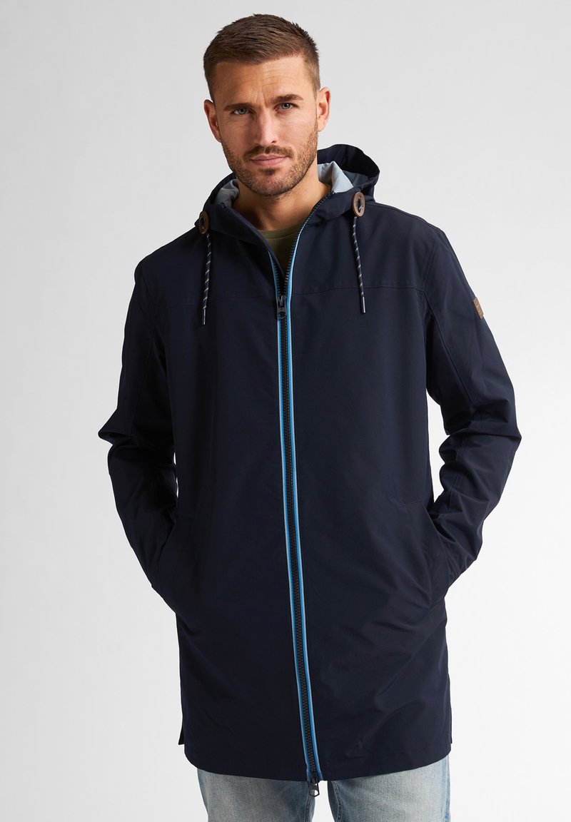Granatowa wodoodporna kurtka z zamkiem błyskawicznym z przodu, niebieskimi akcentami, kapturem ze sznurkiem i dwiema bocznymi kieszeniami. Gładka tekstura i długi krój.