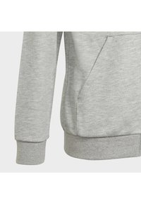 Szary sweter z miękką teksturą, z długim rękawem wykończonym ściągaczem oraz kieszenią typu kangur na przedniej stronie.