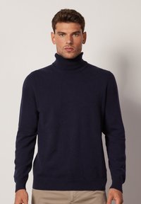 Mörkblå polotröja i mjukt material, med långa ärmar, ribbade mudd och nederkant, samt en figurnära silhuett.