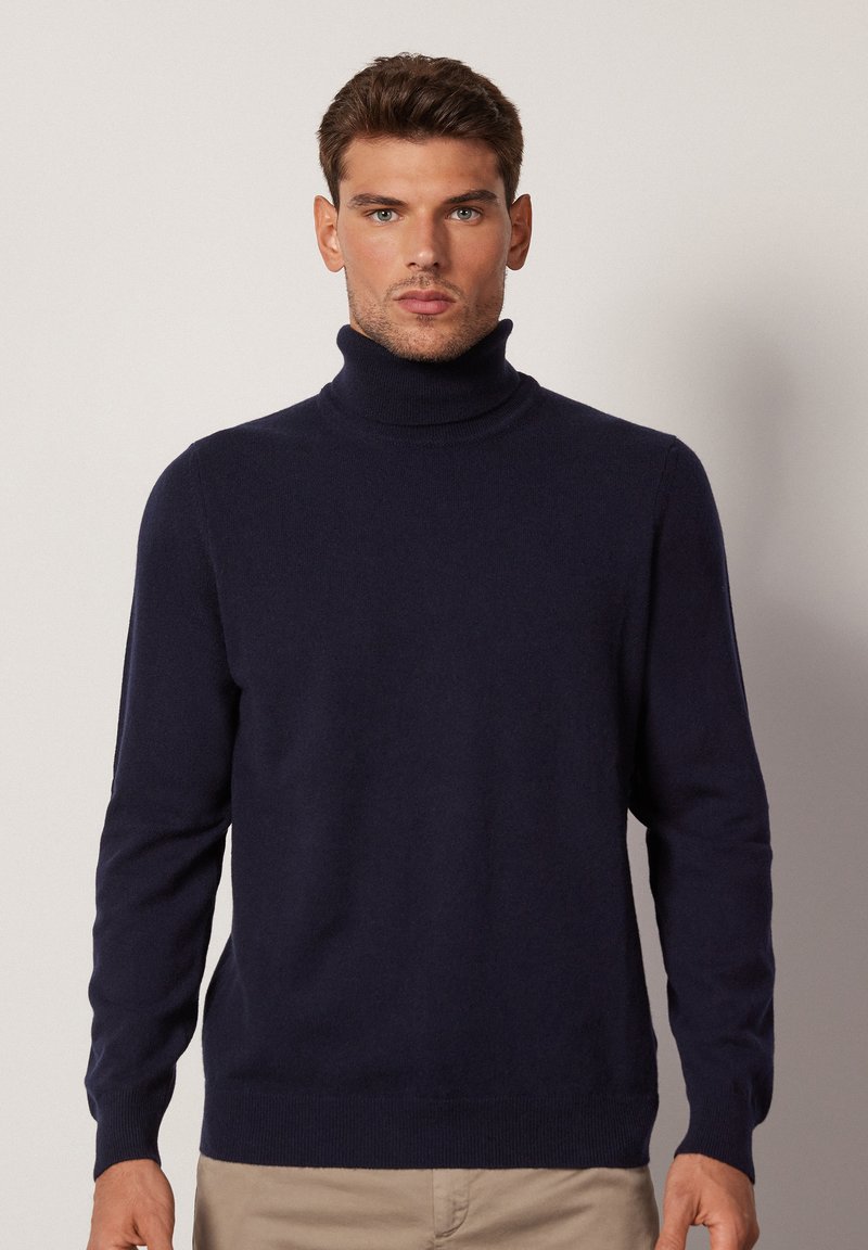 Mörkblå polotröja i mjukt material, med långa ärmar, ribbade mudd och nederkant, samt en figurnära silhuett.