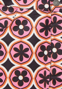 Motif de tissu avec des hexagones roses contenant des fleurs noires à cinq pétales avec des centres blancs, des bordures orange et des formes en losange entre les hexagones.